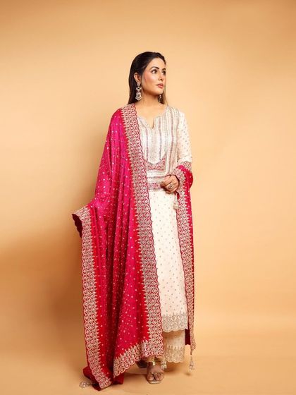 A model looks elegant in an ivory Anarkali suit by Faabiiana, paired with a vibrant pink embroidered dupatta for a pop of color.