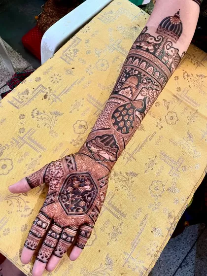 An intricate bridal arm design with a variety of elements. It includes peacocks, elephants, and a central hexagonal motif for a unique touch.