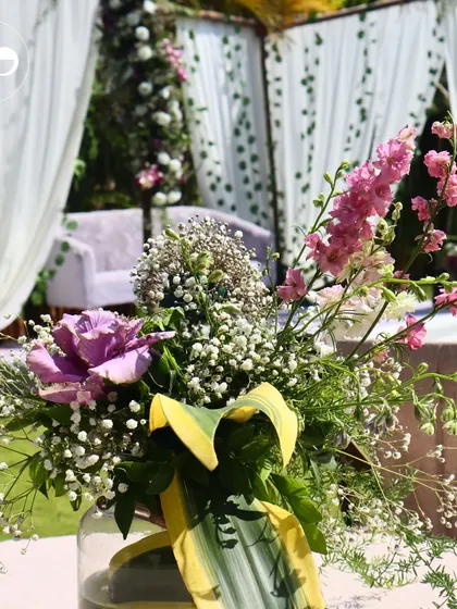 A beautiful centerpiece with pink and purple flowers, reflecting the color palette of a romantic outdoor Roka ceremony.