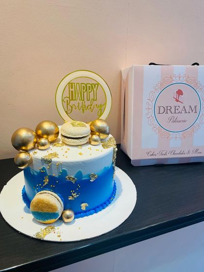 A stylish blue and gold cake, featuring a blue ombre design, gold leaf, and macarons. This cake comes with our signature packaging, perfect for gifting.