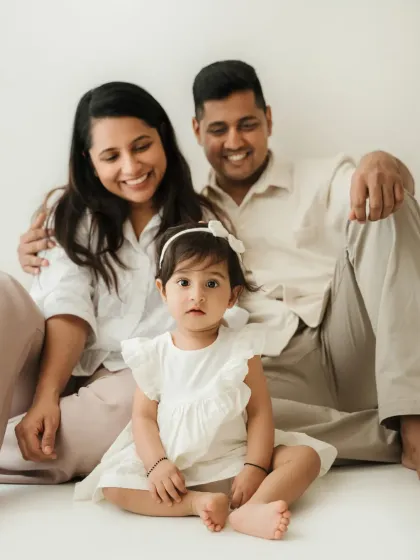 A happy family portrait with the baby girl front and center. Her direct gaze at the camera makes this an engaging and sweet photo.