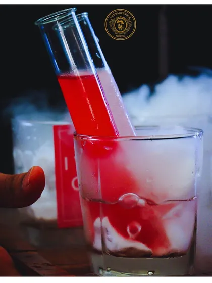 A fiery and smoky red cocktail served in a test tube. This is a prime example of our molecular mixology, designed to create a dramatic and memorable experience.