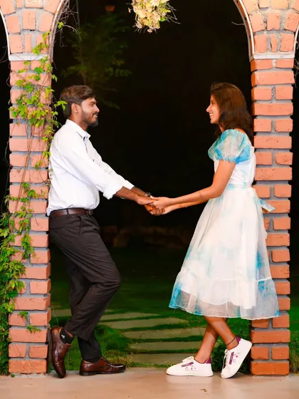 A romantic moment captured between two brick arches. The warm lighting and natural setting create an intimate and sweet atmosphere.