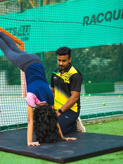 A young gymnast practices a wall-assisted handstand, a great drill for building the strength and confidence needed for more advanced moves.