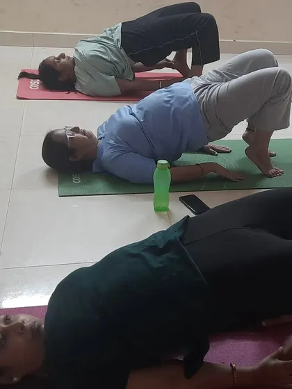 Students from a women's yoga class practicing Setu Bandhasana (Bridge Pose).