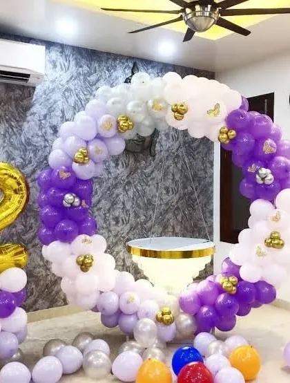 A circular balloon frame decorated with purple, white, and gold balloons. A large gold foil number '2' marks the milestone.
