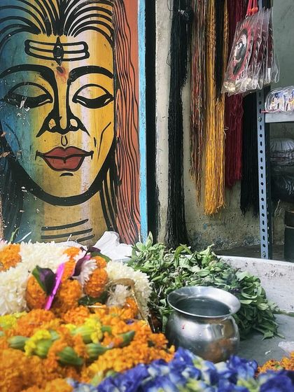 The vibrant colors of a streetside shrine in Varanasi, with a painting of Lord Shiva and fresh flower offerings.