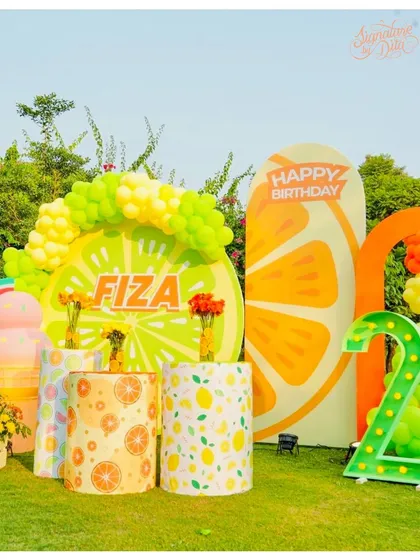 Another angle of the 'Two-tti Fruity' backdrop, showing the custom-printed pedestals used for displaying cakes or gifts.