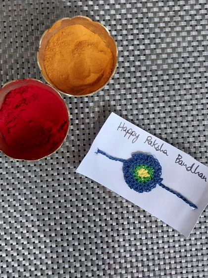 A multicolored crochet rakhi with a yellow center. A small but vibrant handmade rakhi.