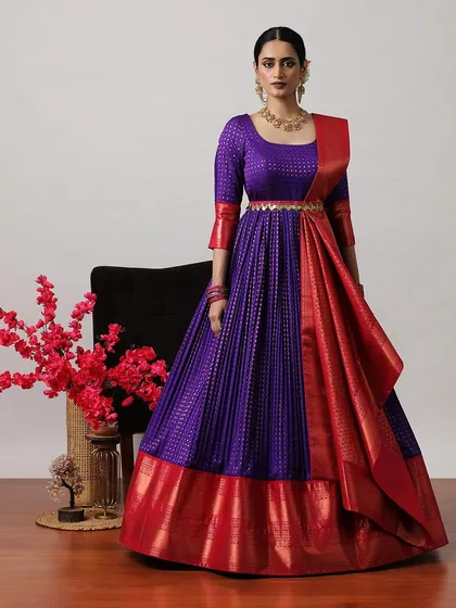 A regal purple and red half-saree style gown, featuring a pleated skirt and a rich Banarasi border. The three-quarter sleeves add a touch of elegance.