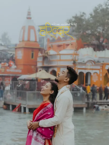 A beautiful portrait of the couple in Haridwar, looking up with joy, with a temple and the ghats in the background.