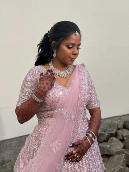 A beautiful outdoor shot of Surya. Her pink lehenga and shimmery makeup look stunning in the natural light.