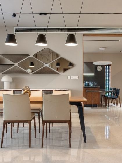 This view across the dining table highlights the sleek, modern chairs and the geometric shelving and mirror unit, which serves as both storage and a decorative feature.