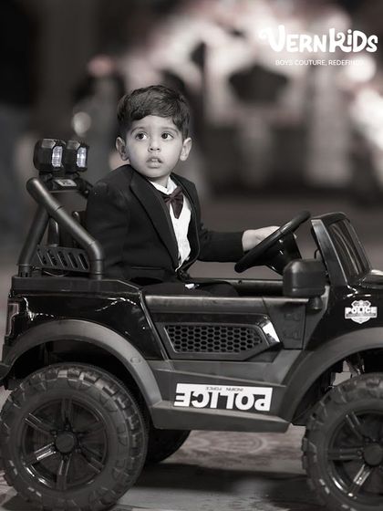 The little boss. A classic black tuxedo with a burgundy bow tie is a timeless choice for a milestone birthday, making him look sharp and feel important.