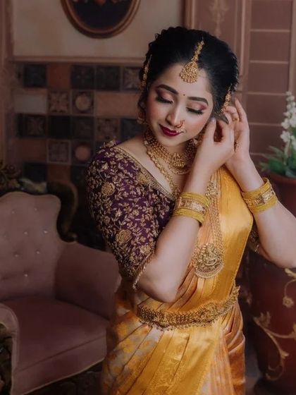 A close-up of a beautiful bride in a yellow silk saree and a contrasting purple embroidered blouse. The zardosi work on the blouse is completely customized.