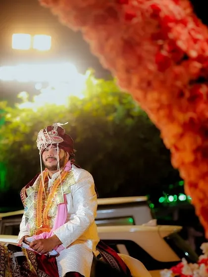 A low-angle shot of the groom on his horse, framed by the floral entrance decor. This perspective makes the moment feel even more grand and celebratory.