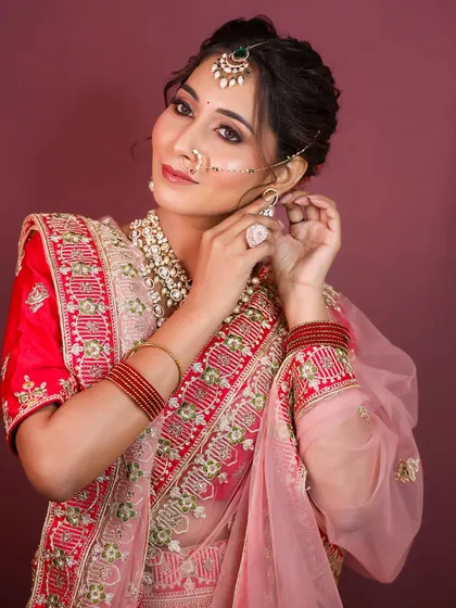 Adjusting the jhumkas, this shot gives a closer look at the detailed jewelry and the soft, elegant updo.