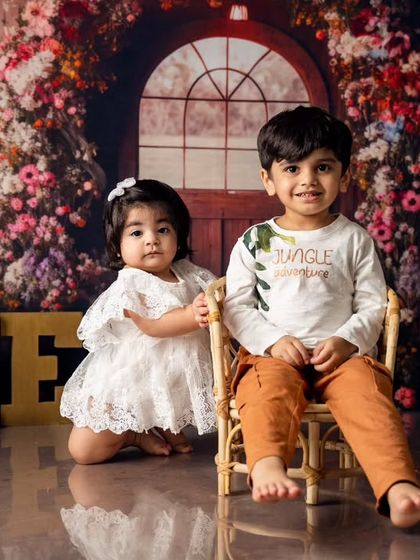 A proud big brother sits with his sister as she celebrates turning one. Our floral-themed shoots create a beautiful setting for these heartwarming family moments.