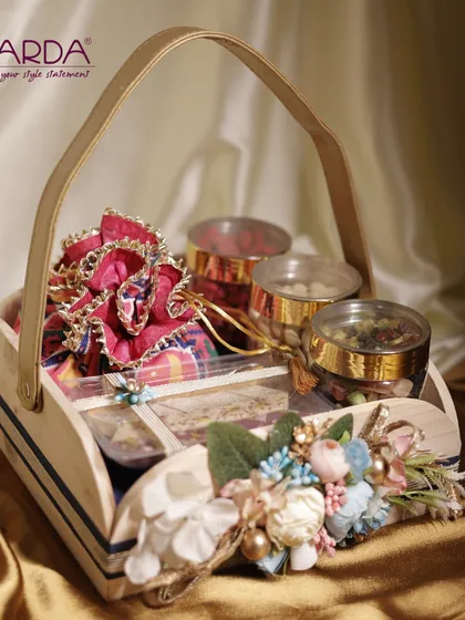This unique gift hamper is presented in a charming wooden basket, adorned with delicate floral arrangements. It’s filled with an assortment of gourmet nuts and traditional sweets, making it a beautiful and rustic-chic gift for any celebration.
