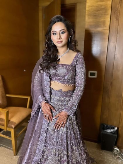 A stunning engagement bride with her hair in soft, open waves. This classic style highlights her features and complements her beautiful lavender lehenga.