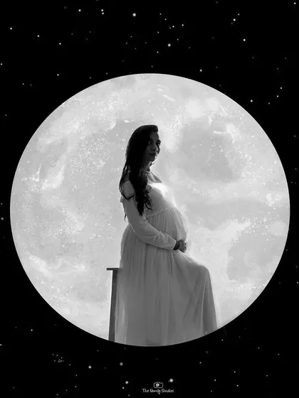 A creative and artistic silhouette of a pregnant woman against a full moon. This black and white composite image is a beautiful example of the unique, edited art pieces we can create.