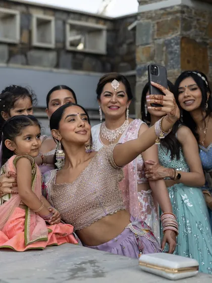 The bride takes a happy selfie with her family and bridesmaids, a modern and candid moment that captures the joy of being surrounded by loved ones.