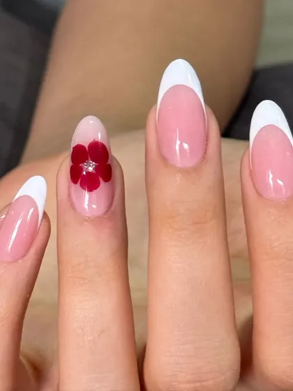 A closer look at the elegant white French manicure with a single, detailed 3D red flower accent nail.