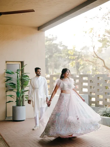 A beautiful shot of the bride twirling in her lehenga as she holds her groom's hand. The natural light and her joyful movement create a magical photo.