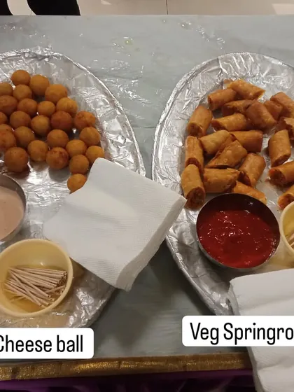Classic party starters that everyone loves. On the left are crispy Cheese Balls with dip, and on the right are Veg Spring Rolls with ketchup.