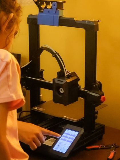 A young girl operates the 3D printer, selecting the file to print. I make sure kids are involved in every step of the process, from design to final production.