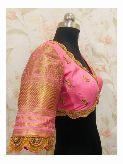 A side view of the pink blouse, highlighting the embroidered scalloped edge on the sleeve cuff, which matches the back design.