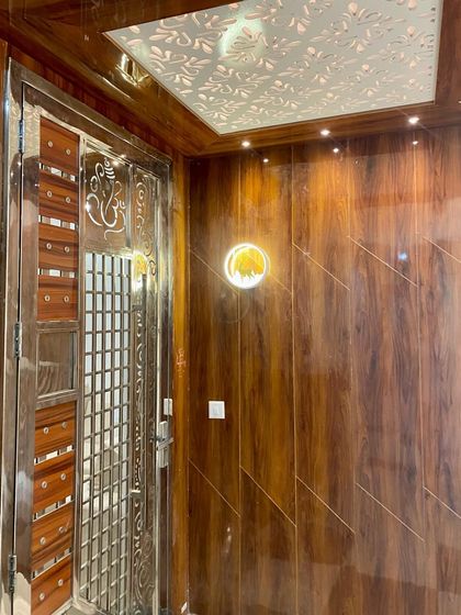 A beautiful main door entrance with full wood-panelled walls and a CNC-cut ceiling panel. The stainless steel security door adds a layer of safety.