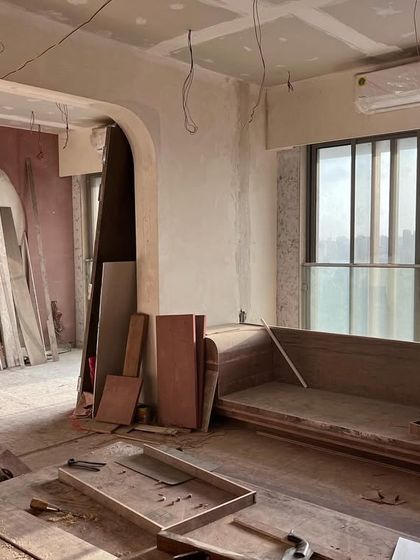 A work-in-progress shot of the living room. Here you can see the bare structure of the custom-built swing sofa and the arched entryway taking shape, the foundational elements of what will become a tranquil, traditional home.