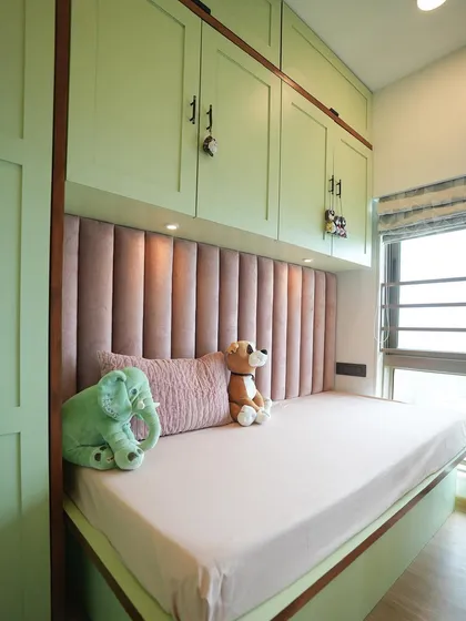 We chose gender-neutral colors for this nursery, with a soft green wardrobe and a plush pink fluted headboard for the daybed.