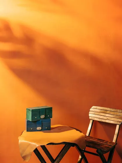 An atmospheric shot of Verman Atelier's leather boxes on a table, with dramatic shadows creating a sense of mood and mystery. This image sets a sophisticated tone for the brand.