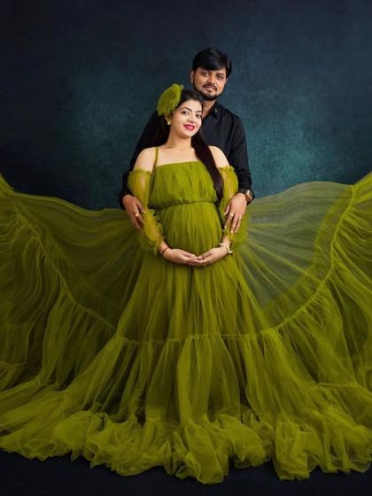 A dramatic and powerful couple's portrait. The olive green tulle gown with its incredible spread creates a stunning visual, making this studio maternity shoot truly one-of-a-kind.