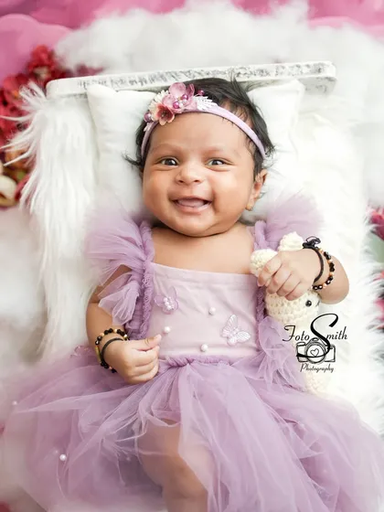 A huge, happy smile from this beautiful baby girl. Dressed in a lovely purple dress, her joy is absolutely infectious. Capturing a newborn's smile is a true treasure.