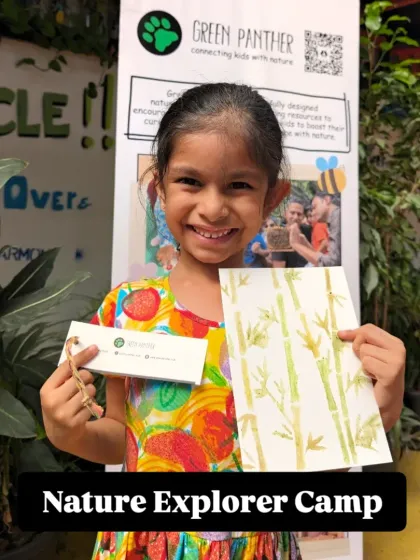 A happy explorer shows off her bamboo painting and a nature journal, proud of the beautiful things she created at our camp.