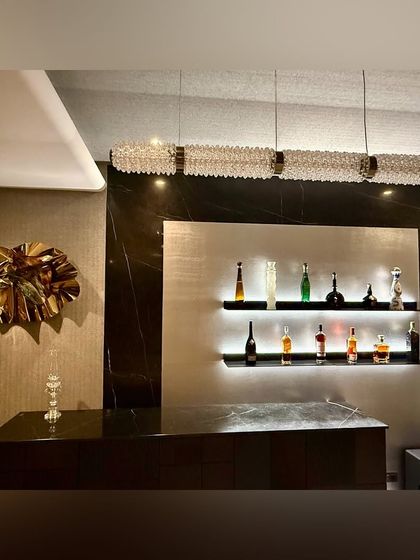 A custom sculptural wall art piece in gold-toned steel, designed as a bold focal point for a client's home bar.