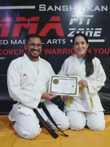 Another student proudly receives her certificate and new belt after a successful karate grading. Each belt represents a new level of skill and responsibility.