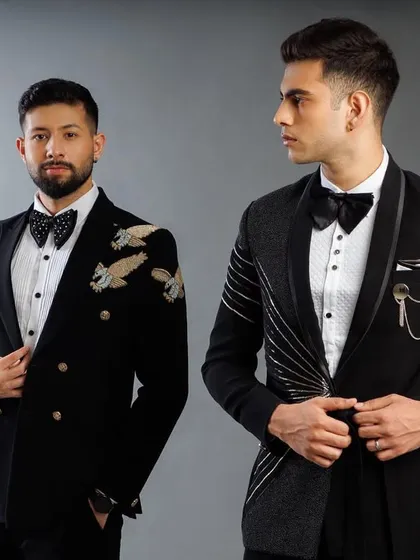 Two of our signature looks. On the left, a double-breasted tuxedo with eagle embroidery. On the right, our modern draped tuxedo with chain accessory.