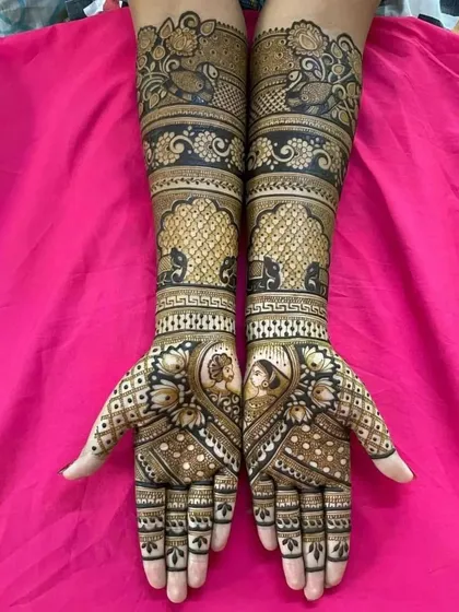 A beautiful design with small couple portraits in the palms, surrounded by intricate jaali work and peacock and elephant motifs on the arms.