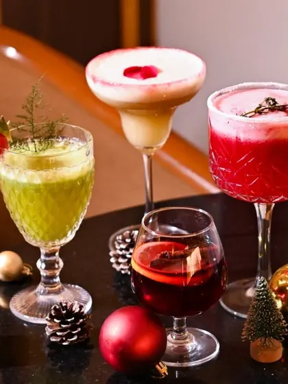 A festive collection of Christmas cocktails, including red, green, and mulled wine varieties, surrounded by holiday ornaments. This shot is perfect for a seasonal menu or holiday promotion.
