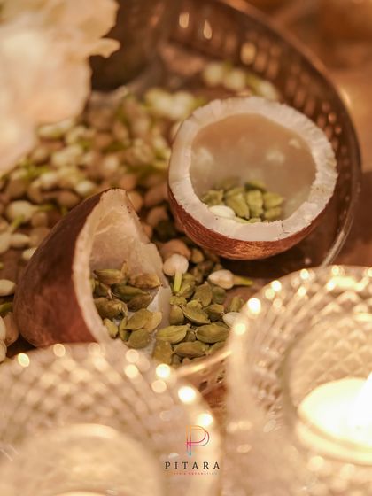 Traditional elements with an elegant touch. A silver platter with dried coconut halves filled with cardamom, surrounded by fragrant jasmine buds.