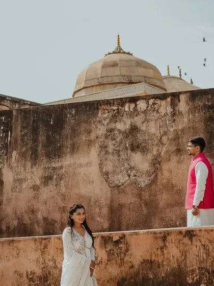 Capturing the scale of Rajasthan's forts is key to our style. Here, we positioned the couple against the rustic walls of Amer Fort with birds in flight, adding a touch of dynamic life to this heritage pre-wedding photo.