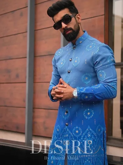 Modern tradition in a striking shade of blue. This custom bandhgala kurta set features intricate geometric patterns, offering a fresh, contemporary take on classic ceremonial wear. It is designed for the man who leads with style.