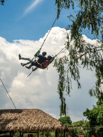 Two people on the Sky Swing against a beautiful cloudy sky, creating a picture-perfect adventure moment.