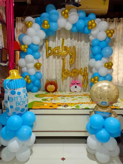 A classic 'Welcome Baby Boy' decoration for a home. We created a balloon arch around a seating area with foil balloons and props like a teddy bear.
