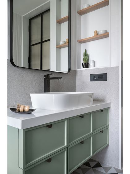 A close-up of the mint green vanity in the master bathroom. The clean lines, shaker-style drawers, and minimalist black hardware contribute to the room's fresh and modern feel.