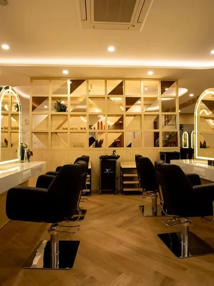 A closer look at the main styling area, where functionality meets luxury. The custom-made, backlit arched mirrors provide perfect lighting for stylists, while the clean white countertops and comfortable seating ensure a premium experience for every client.
